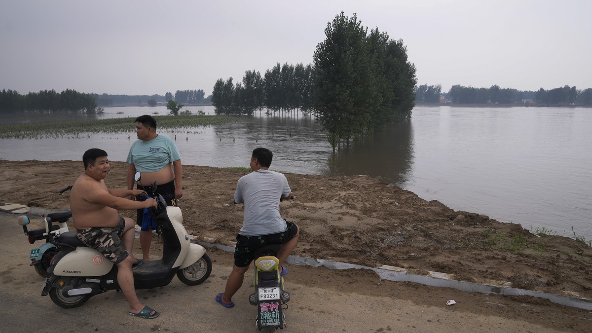 Villagers look over a swollen river which floods the crops at a village in Langfang in Hebei province, China Wednesday, Aug. 2, 2023. (AP Photo/Andy Wong)