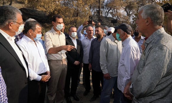 In this photo released Tuesday, Oct. 13, 2020 on the official Facebook page of the Syrian Presidency, Syrian President Bashar Assad, third from left, wearing a mask to help prevent the spread of the c ...