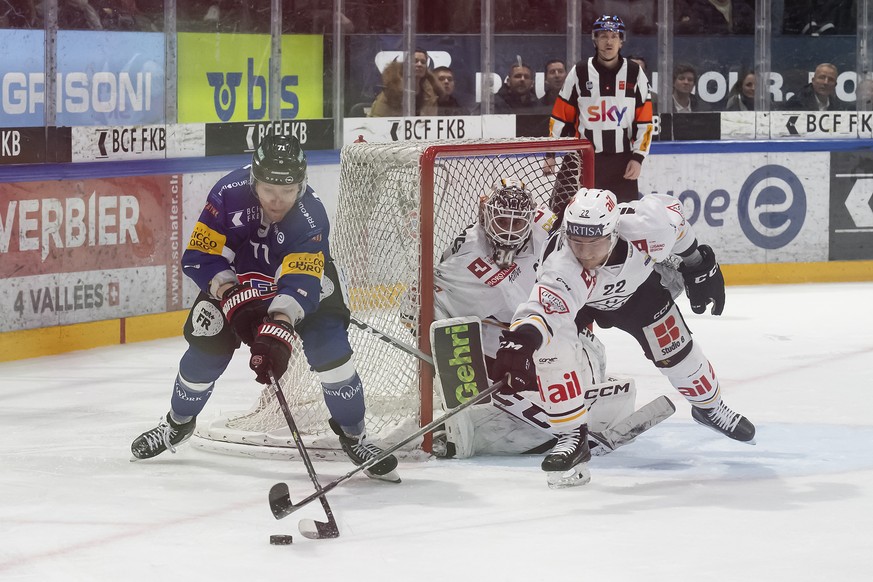 Fribourgs Killian Mottet, links, und Luganos Santeri Alatalo, rechts, kaempfen um den Puck neben Luganos Torhueter Niklas Schlegel, Mitte, im dritten Eishockey Playoff Viertelfinal Spiel der National  ...