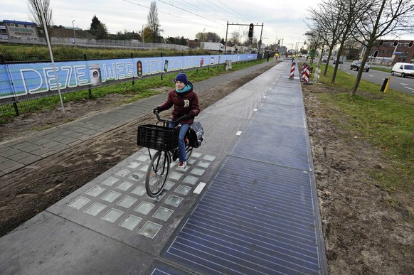 epa04486581 A cyclist drives on the SolaRoad, the first road in the world made of solar panels, during the official opening in Krommenie, the Netherlands, 12 November 2014. The solar energy that will  ...
