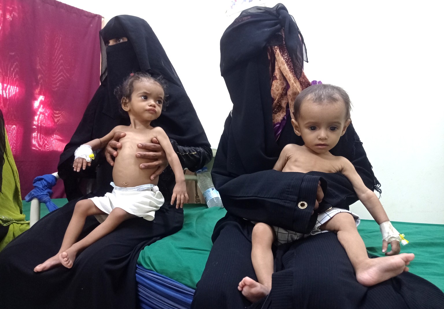 FILE - Women hold their malnourished children at Hays Rural Hospital in Hodeida, Yemen, Oct. 11, 2022. In many Middle Eastern and African nations, climatic shocks killed hundreds and displaced thousan ...