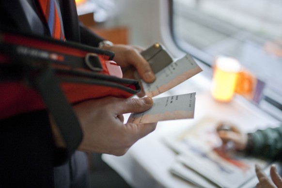 A ticket collector punches two tickets in an InterCity train of the Swiss Federal Railways SBB from Berne to Biel, Switzerland, on November 27, 2009. (KEYSTONE/Gaetan Bally) 

Ein Kondukteur kontrolli ...