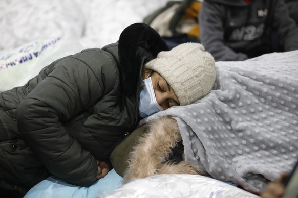 epa09589411 People settle for the night inside the transport and logistics center &#039;Bruzgi&#039; near the the Bruzgi checkpoint at the Belarusian-Polish border, in the Grodno region, Belarus, 18 N ...