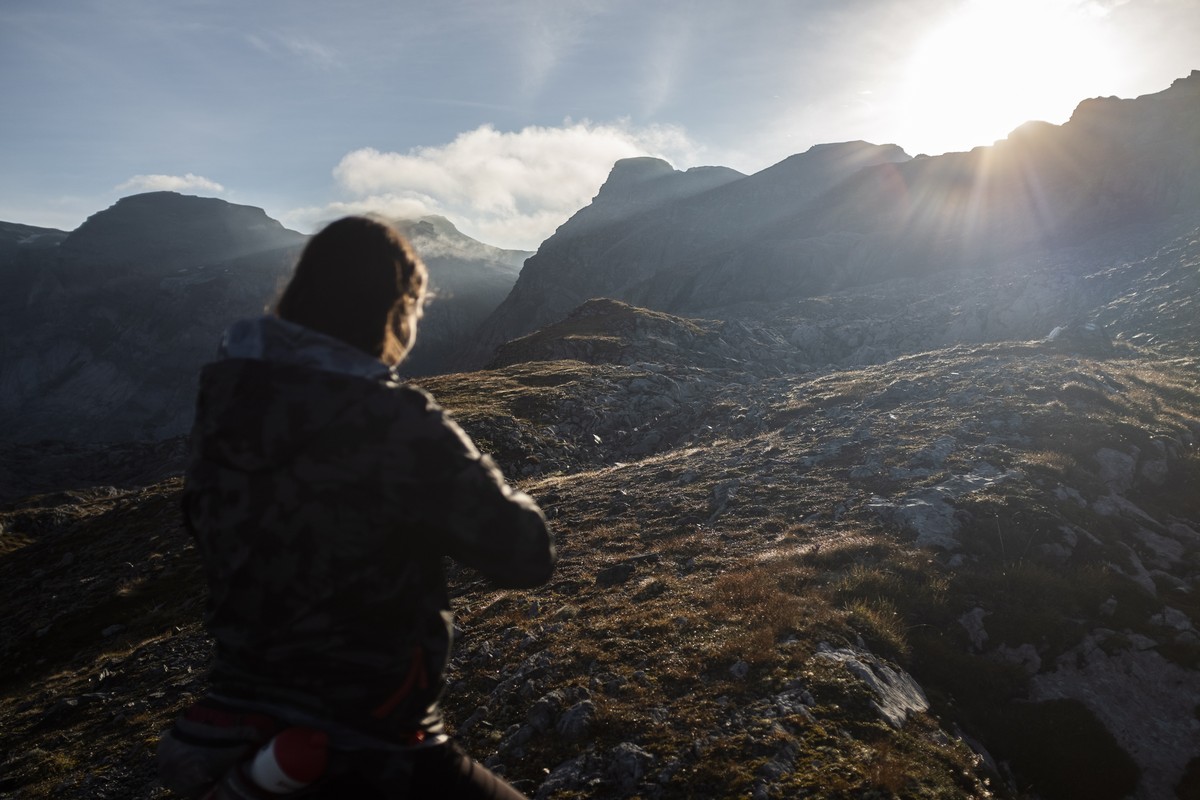 epa08667512 A woman looks into the sunrise while hiking on an alpine trail at Panixerpass in Elm, Switzerland, 13 September 2020. EPA/GIAN EHRENZELLER