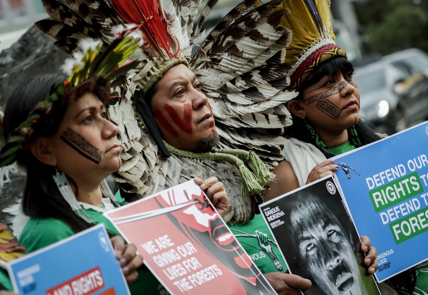 epa07973919 Leaders of Brazilian indigenous communities (L-R) Nara Bare, Celia Xacriaba and Kreta Kaingang pose with protest banners and a portrait of Paulo Paulino Guajajara in front of the European  ...