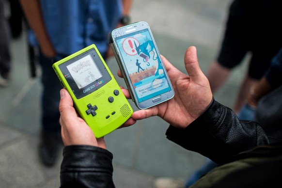 epa05427920 A gamer displays the Pokemon video game on a Game Boy (L) and the Pokemon Go app on a smartphone (R), during a Pokemon Go walk at the Stephansplatz in Vienna, Austria, 16 July 2016. The ga ...