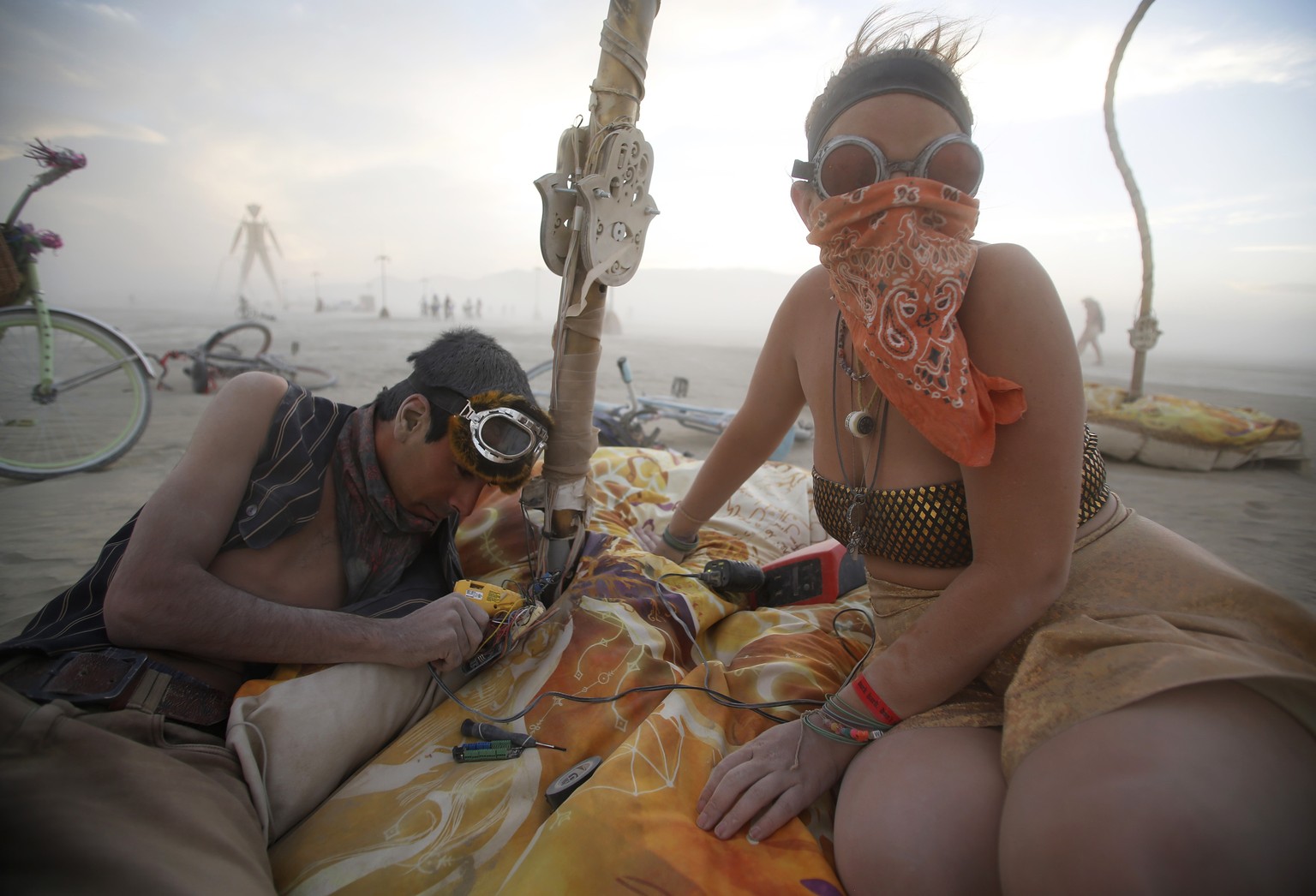 Samuel Clay (L) and Brittany Janis work, amidst the dust, on the electronics for the art installation Pulse &amp; Bloom during the Burning Man 2014 &quot;Caravansary&quot; arts and music festival in t ...