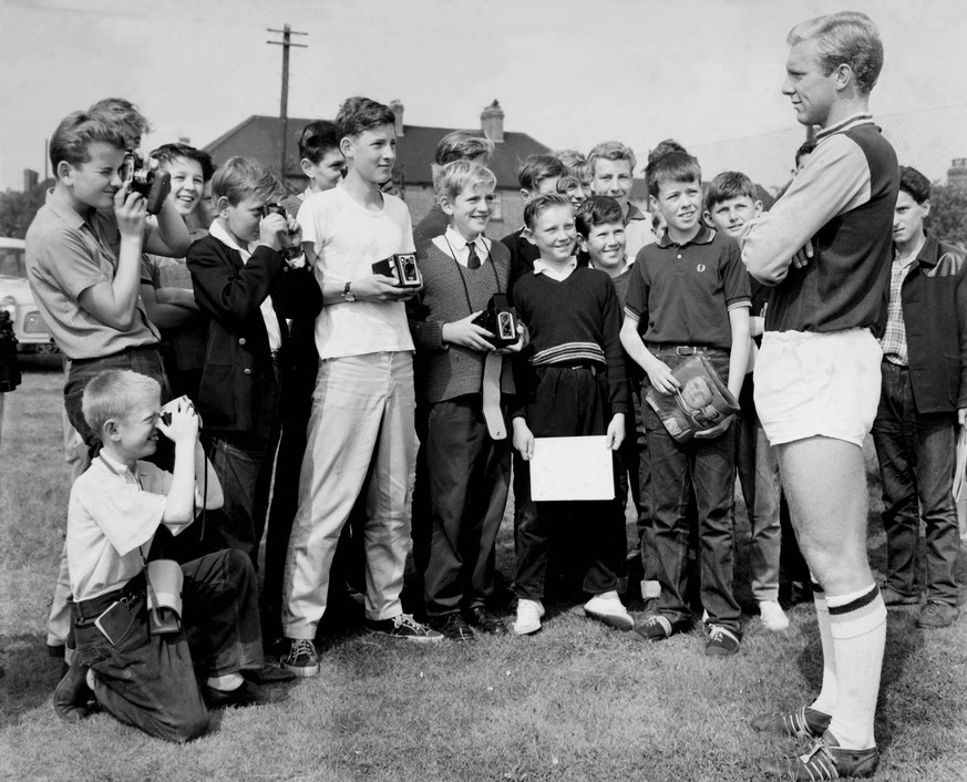 The West Ham United Footballers are now in training for the coming season at their newly acquired ground at Chadwell Heath, Essex. Photograph Shows - young admirers photograph their idol Bobby Moore.  ...