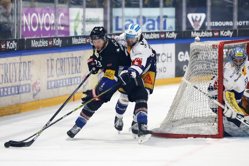 Gotterons Samuel Walser, links, und Zugs Dominik Schlumpf in Aktion, hinter dem Tor von Zugs Torhueter Luca Hollenstein, im Eishockey Meisterschaftsspiel der National League zwischen dem HC Fribourg G ...