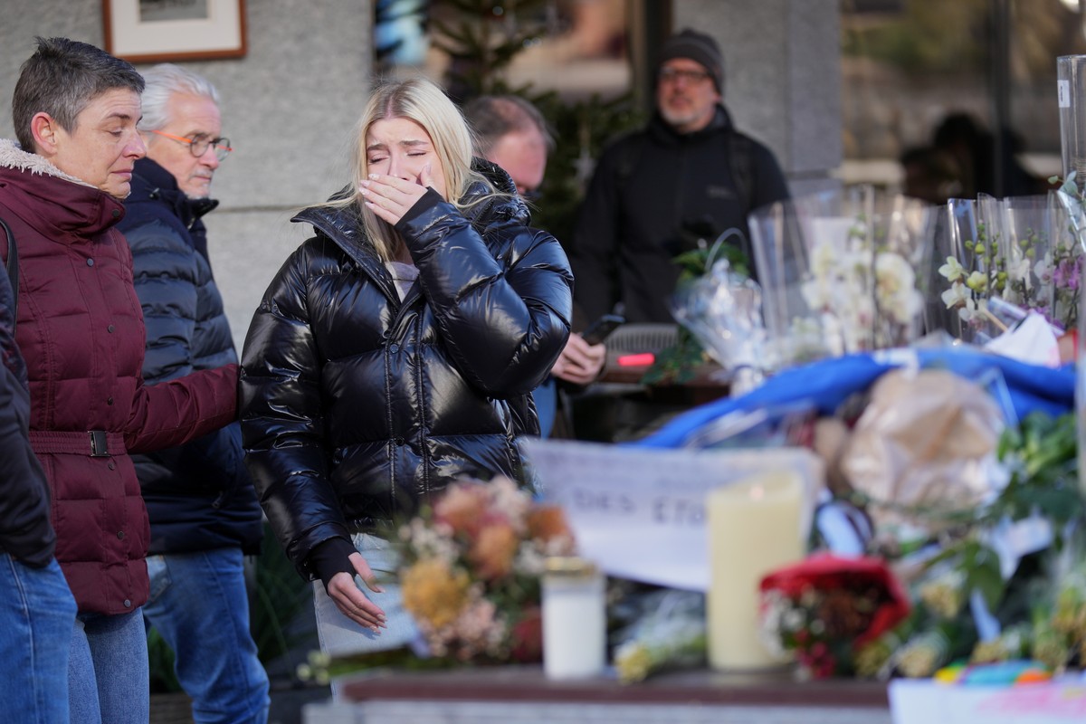 People bring flowers near the sealed off Le Constellation bar, where a devastating fire left dead and injured during the New Year's celebrations in Crans-Montana, Swiss Alps, Switzerland, Friday, ...