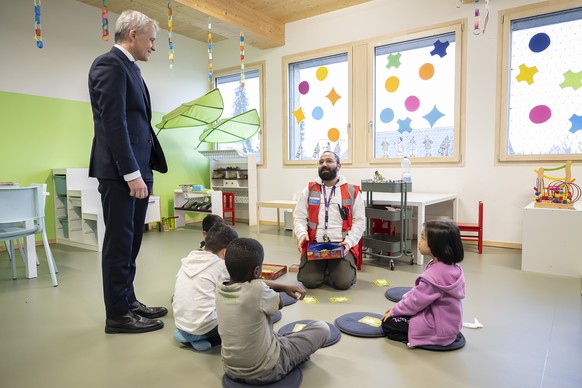 Bundesrat Beat Jans, links, spricht mit einem Mitarbeiter und Asylbewerberkinder bei einem Besuch des Bundesasylzentrums Basel, am Freitag, 19. Januar 2024 in Basel. (KEYSTONE/Anthony Anex)