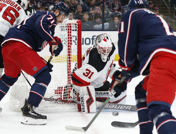 New Jersey Devils&#039; Gilles Senn, center, of Switzerland, makes a save between Columbus Blue Jackets&#039; Nick Foligno, left, and Kevin Stenlund, of Sweden, during the second period of an NHL hock ...