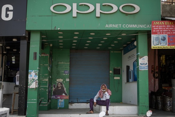 FILE- A man speaks on his mobile phone in front of a shop selling Oppo phones in Noida, outskirts of New Delhi, India, Thursday, June 18, 2020. Indian investigators have raided an Indian subsidiary of ...