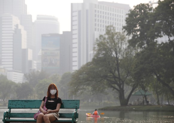 epa10513498 A woman sits on a bench as high-rise buildings are shrouded in smog and a haze of heavy fine dust at Lumpini Park in Bangkok, Thailand, March 10, 2023. Severe air pollution mainly caused by…