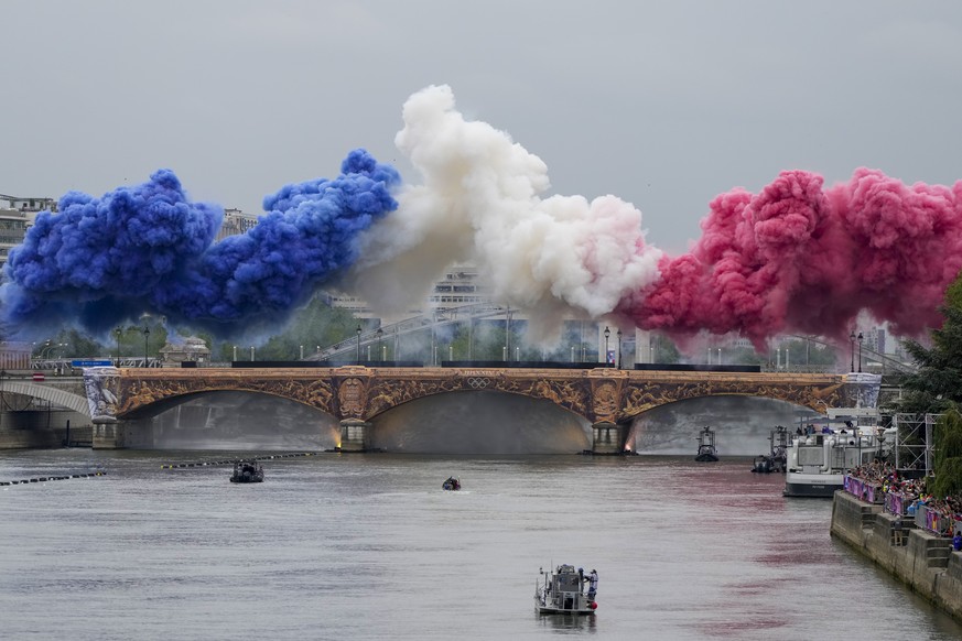 Ceremonial smoke in the colors of the France flag appear over the Seine River in Paris, France, during the opening ceremony of the 2024 Summer Olympics, Friday, July 26, 2024. (AP Photo/Matthias Schra ...