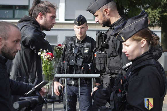 Police officers check men at the entrance of the Gambetta high school, Monday, Oct. 16, 2023 in Arras, northern France. French President Emmanuel Macron was holding Monday a special security meeting a ...