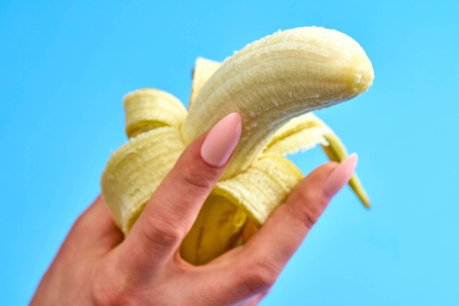 Augsburg, Bavaria, Germany - March 21, 2024: A woman s hand holds a peeled banana *** Die Hand einer Frau h�lt eine gesch�lte Banane