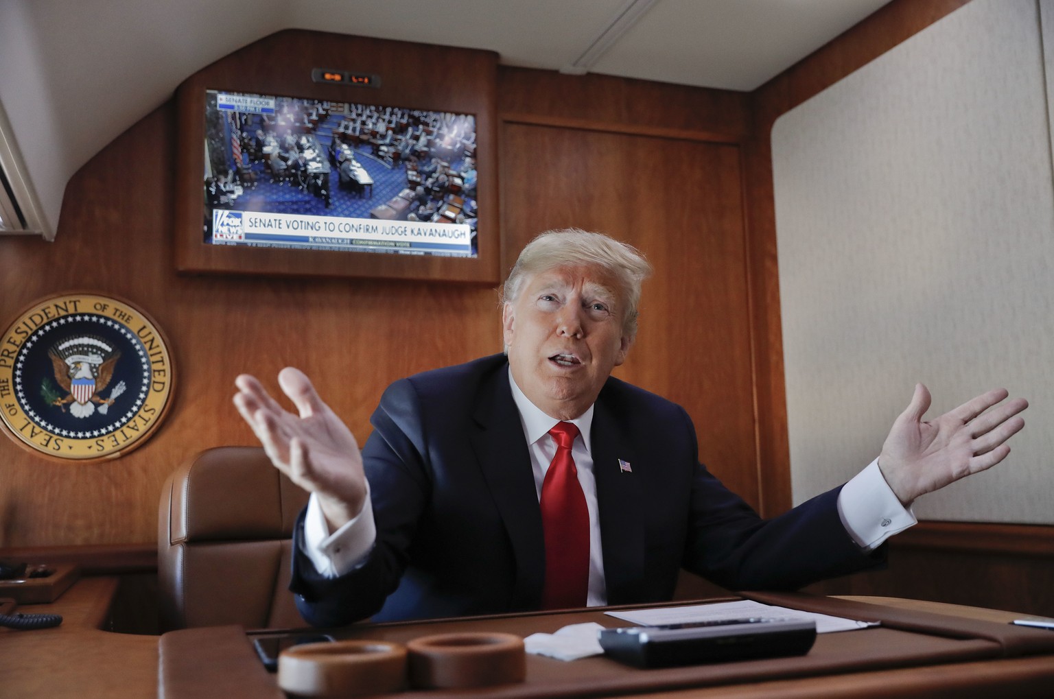 FILE - In this Oct. 6, 2018, file photo, President Donald Trump, on board Air Force One, gesture while watching a live television broadcast of the Senate confirmation vote of Supreme Court nominee Bre ...