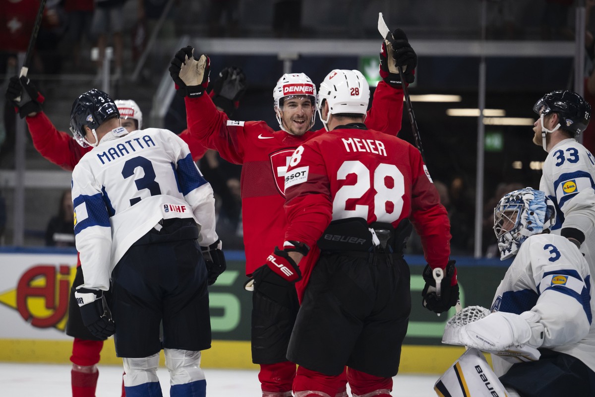 Switzerland's Ken Jager, center, celebrates with teammate Timo Meier after scoring his side's third goal during the 2026 IIHF Men's Ice Hockey World Championship preliminary round group ...