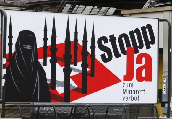 Ein Passant geht an einem Plakat vorbei, welches ein Minarettverbot in der Schweiz fordert, waehrend ein anderes, im Hintergrund, Touristen in der Schweiz willkommen heisst, am Montag, 26. Oktober 200 ...