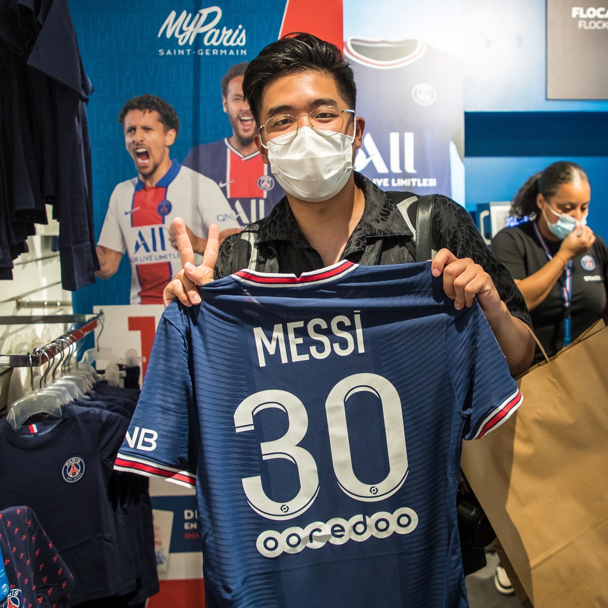 epa09409836 A customer pose for photographs after buying the new 'Messi 30' jersey at the official Paris Saint-Germain (PSG) store on the Champs Elysee avenue in Paris, France, 11 August 202 ...