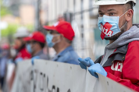 Des personnes portant des masques faciaux de protection manifestent lors dÕune action du syndicat Unia contre lÕinterdiction des syndicats dÕacceder aux chantiers pour controler les normes de lÕOFSP s ...