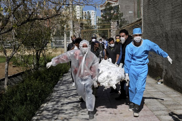 People wearing protective clothing carry the body of a victim who died after being infected with the new coronavirus at a cemetery just outside Tehran, Iran, March 30, 2020. The new coronavirus causes ...