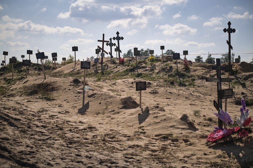 epa10229367 Forensic technicians work at a burial site near the recently recaptured city of Lyman, Donetsk area, Ukraine, 07 October 2022. A burial site with more than 50 graves was found after Ukrain ...