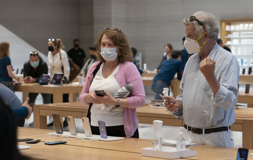 FILE - In this Friday, May 21, 2021, file photo, customers look at the iPhone 12 at an Apple store, in New York. Three tech companies that have amassed unparalleled influence while reshaping the way w ...