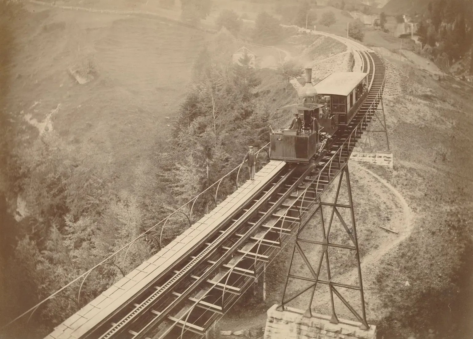 Zugskomposition der Vitznau-Rigi-Bahn um 1875 auf der Schnurtobelbrücke mit gut sichtbarer Leiterstange des «Systems Riggenbach». Ein Zugsläufer ging voraus, um den Lokführer vor Gefahren zu warnen od ...