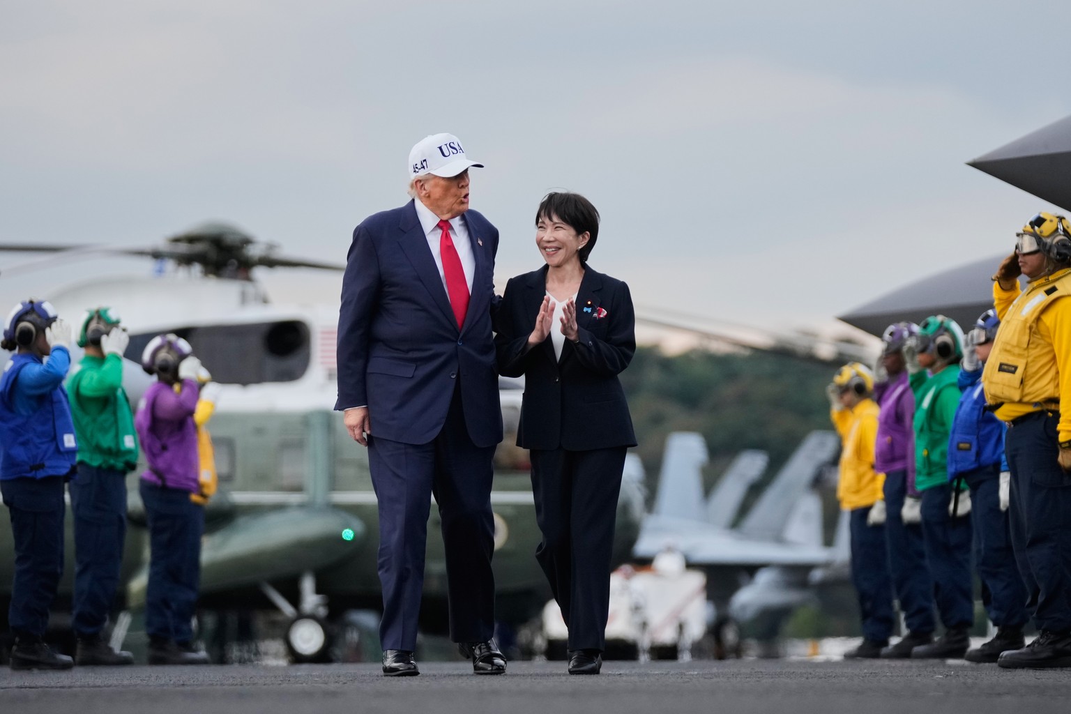 President Donald Trump and Japanese Prime Minister Sanae Takaichi walk on the USS George Washington, an aircraft carrier docked at an American naval base, before speaking to members of the military in ...