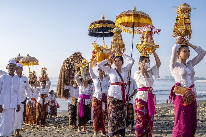 epa10531276 Balinese Hindu people carry &#039;Pratima&#039;, or a symbol of God, while walking on a beach during a cleansing ceremony called &#039;Melasti&#039;, in Denpasar, Bali, Indonesia, 19 March ...