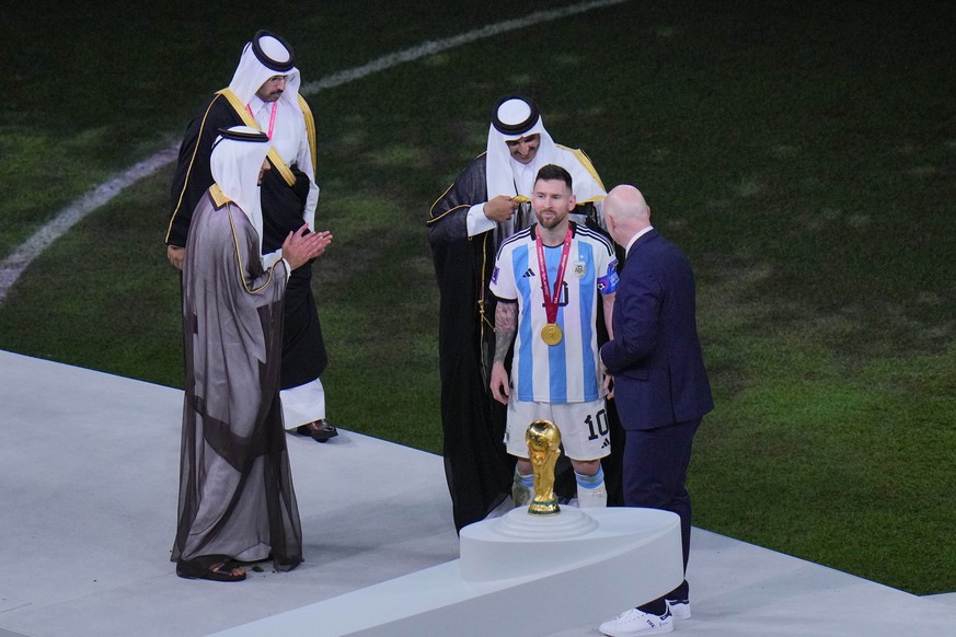 The Emir of Qatar Sheikh Tamim bin Hamad Al Thani puts on a cloak on Argentina&#039;s Lionel Messi after he won the World Cup final soccer match between Argentina and France at the Lusail Stadium in L ...