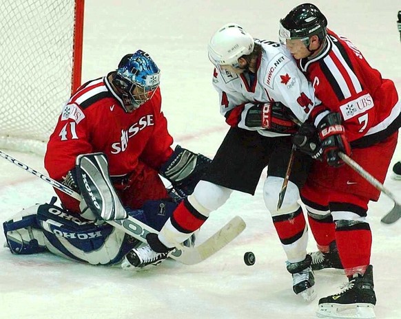 Canada`s Olympic Winner Ryan Smyth, Center, fights for the Puck with Swiss Goalkeeper Lars Weibel, left, and Mark Streit, right, during the second round game between Switzerland and Canada at the Ice  ...