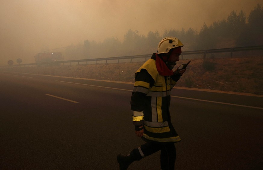 A French fireman walks in the road as smoke fills the sky and blocks the sun as fires burn north of Marseille, France, August 10, 2016. REUTERS/Philippe Laurenson