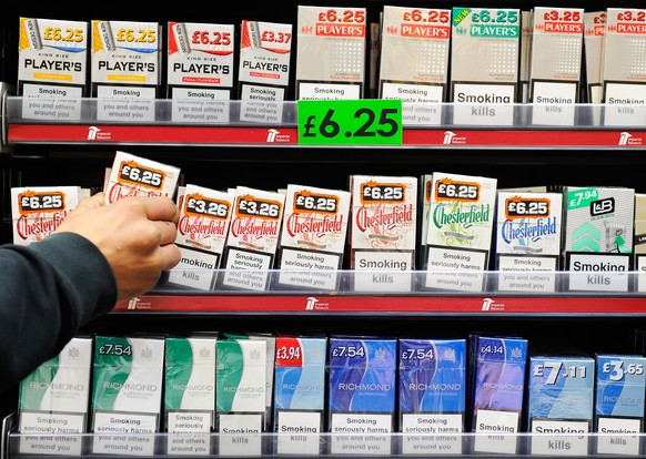epa04575347 A man arranges cigarettes in a grocer's shop in central London, Britain, 22 January 2015. It has been reported that the UK government is planning to introduce legislation for plain ci ...