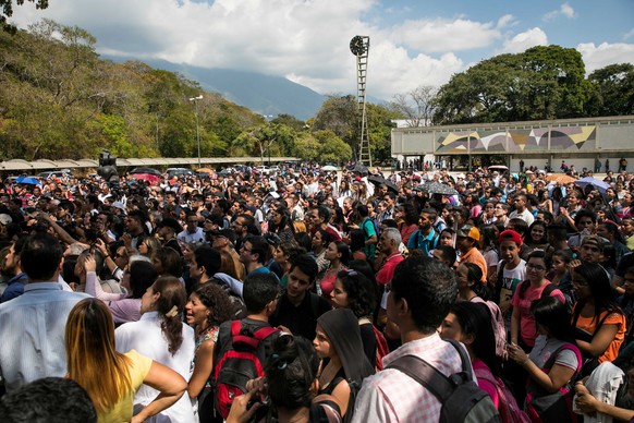 Hunderte Leute hören dem Oppositionspolitiker Juan Guaido zu.
