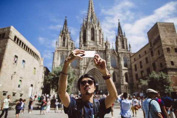 Young asian man taking a selfie in front of the Barcelona Cathedral in Spain.