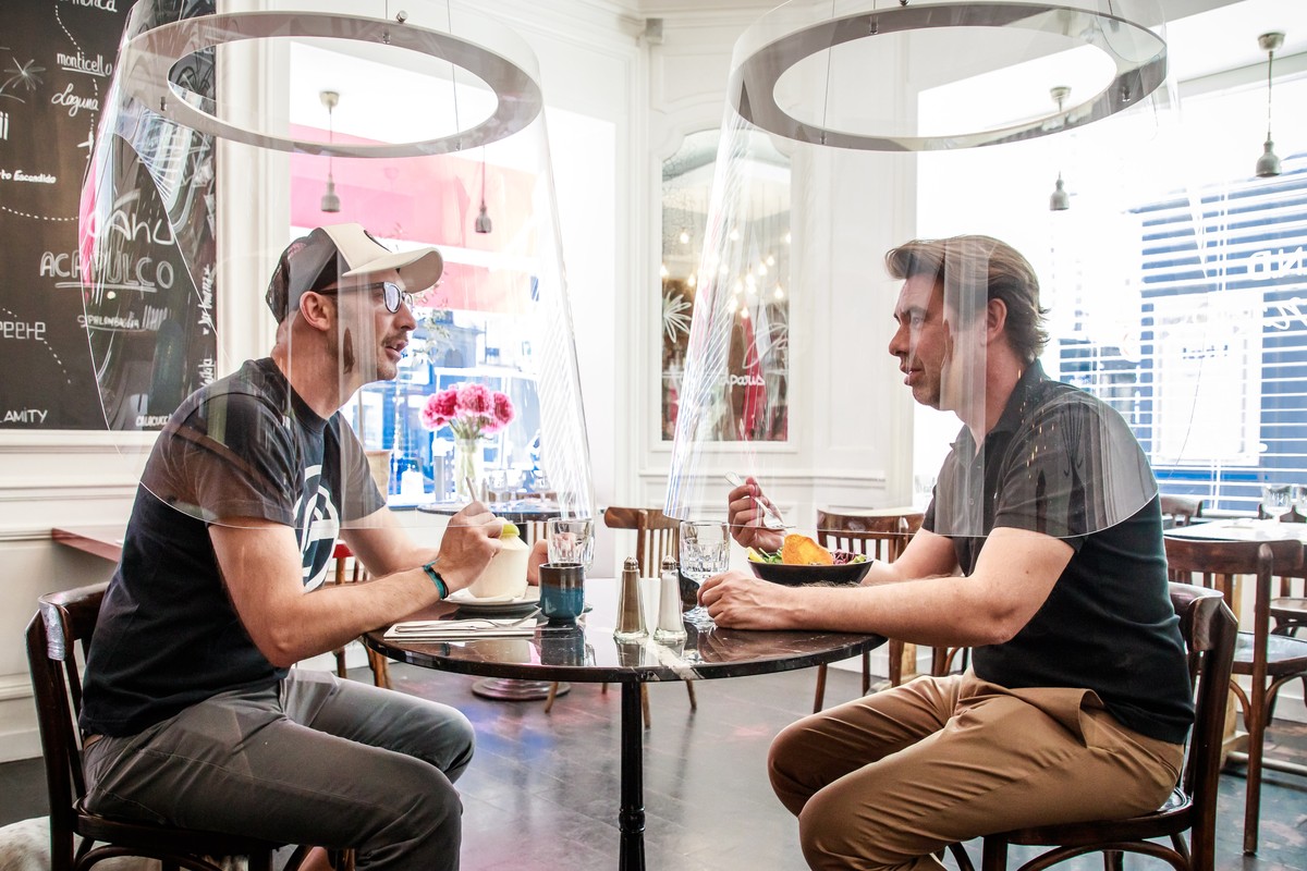 epa08449677 French Designer Christophe Gernigon (R) tries out his creation Plex'Eat, plexiglas bubble which surrounds customers to protect them from the covid-19 infection during a press presenta ...