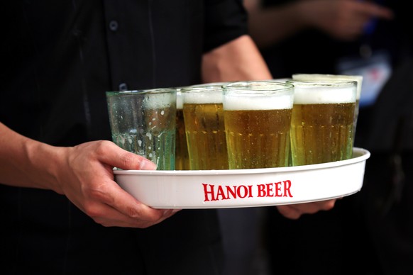 epa10669970 A man brings a tray of Bia hoi or craft beer, which is often referred as Vietnamese street beer, to a table occupied by Australian Prime Minister Anthony Albanese, in Hanoi, Vietnam, 03 Ju ...
