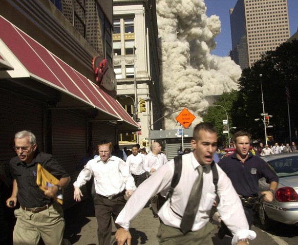 Des piétons fuient la zone du World Trade Center alors que la tour sud du centre s'effondre suite à une attaque terroriste sur le site de New York, mardi 11 septembre 2001.