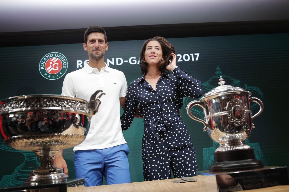 Defending champions Serbia's Novak Djokovic and Spain's Garbine Muguruza pose in front of the cups during the draw of the French Open tennis tournament at the Roland Garros stadium, Friday,  ...