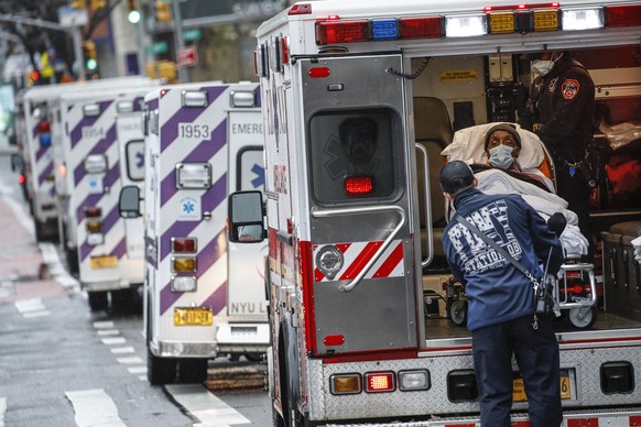 FILE - In this April 13, 2020, file photo, a patient arrives in an ambulance cared for by medical workers wearing personal protective equipment due to COVID-19 concerns outside NYU Langone Medical Center, in New York. The coronavirus has breathed fresh life into old conspiracy theories and inspired a mishmash of new ones, with a cast of villains that includes Bill Gates, 5G wireless technology, the United Nations and President Donald TrumpÄôs political foes. The baseless claims spreading on social media also feature videos taken outside hospitals treating COVID-19 patients. (AP Photo/John Minchillo, File)