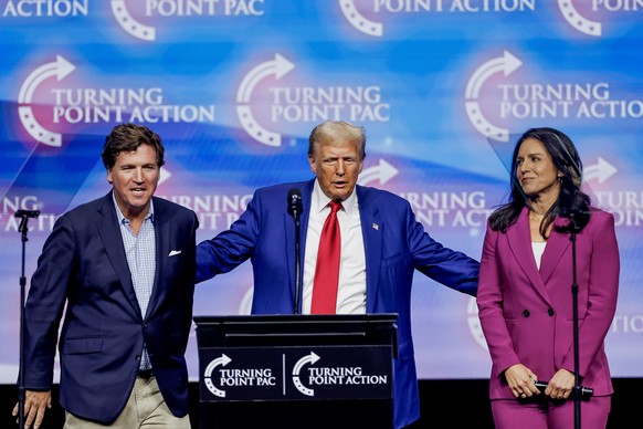 epa11679072 Former US President and Republican presidential nominee Donald Trump (C) with former Hawaii US representative Tulsi Gabbard (R) and conservative commentator Tucker Carlson (L) at the Turni ...