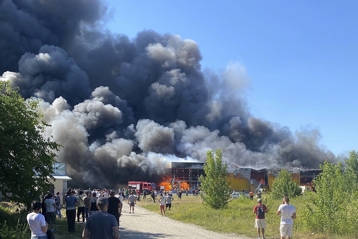 People watch as smoke bellows after a Russian missile strike hit a crowded shopping mall, in Kremenchuk, Ukraine, Monday, June 27, 2022. Ukrainian officials say scores of civilians are feared killed o ...