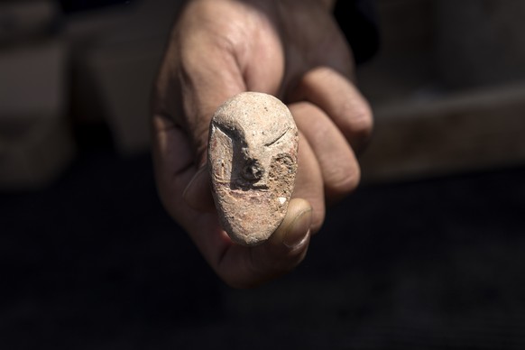 An archeologists shows a figurine found at a large, 5,000-year-old city in northern Israel. Israel&#039;s Antiquities Authority said Sunday the ancient city was discovered during preparations for a ne ...