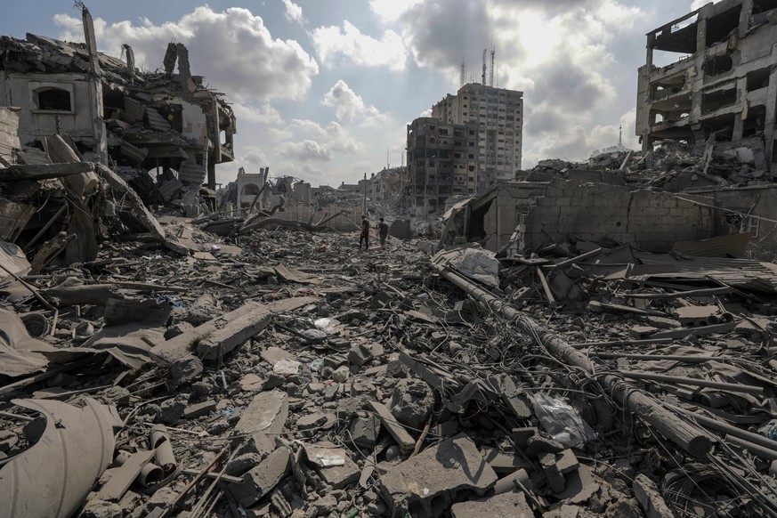 epa10911300 Palestinians walk among the rubble in the destroyed Al-Ramal neighborhood after an Israeli airstrike in Gaza City, October 10, 2023. More than 700 people have been killed and about 4...