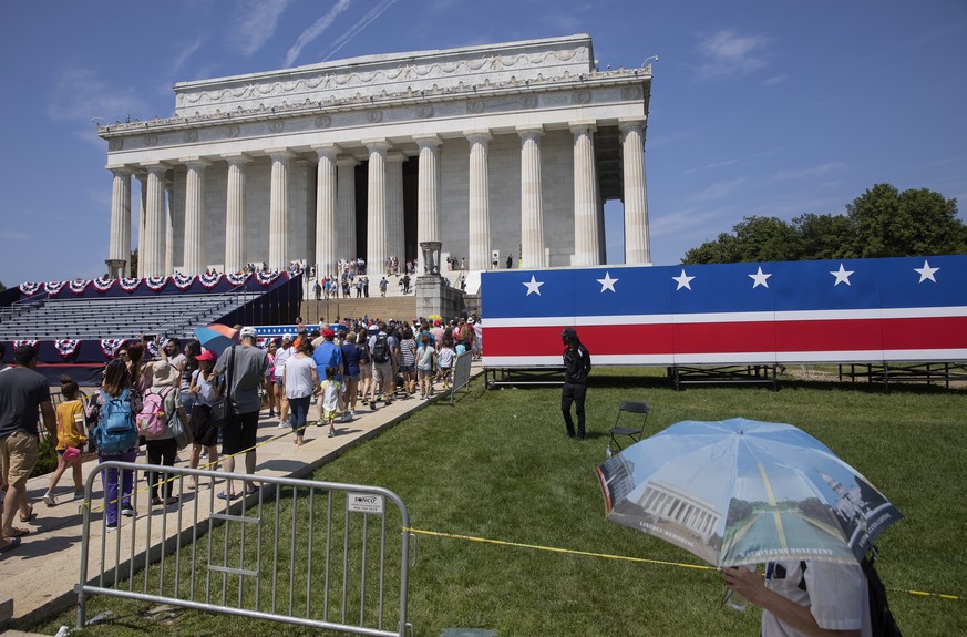 epa07692656 Tourists walk past the temporary decorations and bleachers at the Lincoln Memorial as preparations continue for the US Independence Day celebrations on the National Mall in Washington, DC, ...