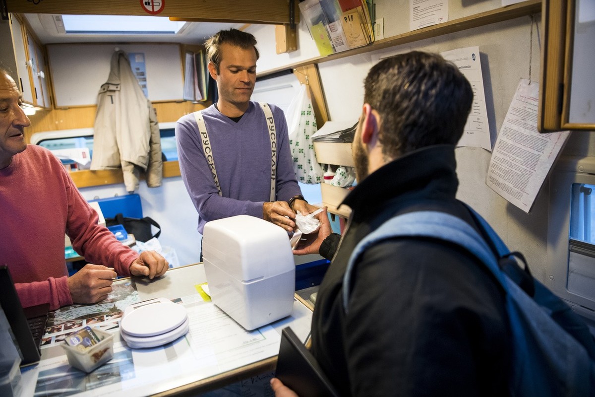 Une personne toxicomane viens chercher du materiel pour une consommation distribue par Vincent, droite, un intervenant social et Sebastien, gauche, un infirmier, dans le bus "Distribus" de l ...