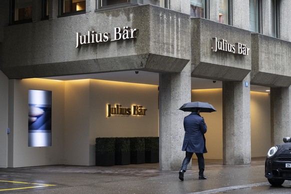 Ein Mann mit Schirm laeuft an der Julius Baer Bank vorbei, aufgenommen am Donnerstag, 1. Februar 2024 an der Bahnhofstrasse in Zuerich. (KEYSTONE/Ennio Leanza)